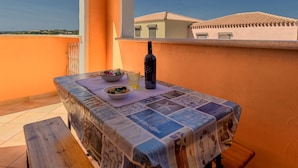 Un balcón con una mesa para dos, una botella de vino y un cuenco de aperitivos.