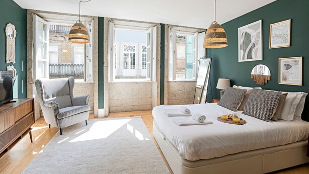 Un dormitorio con cama, una silla, un televisor y obras de arte en la pared.