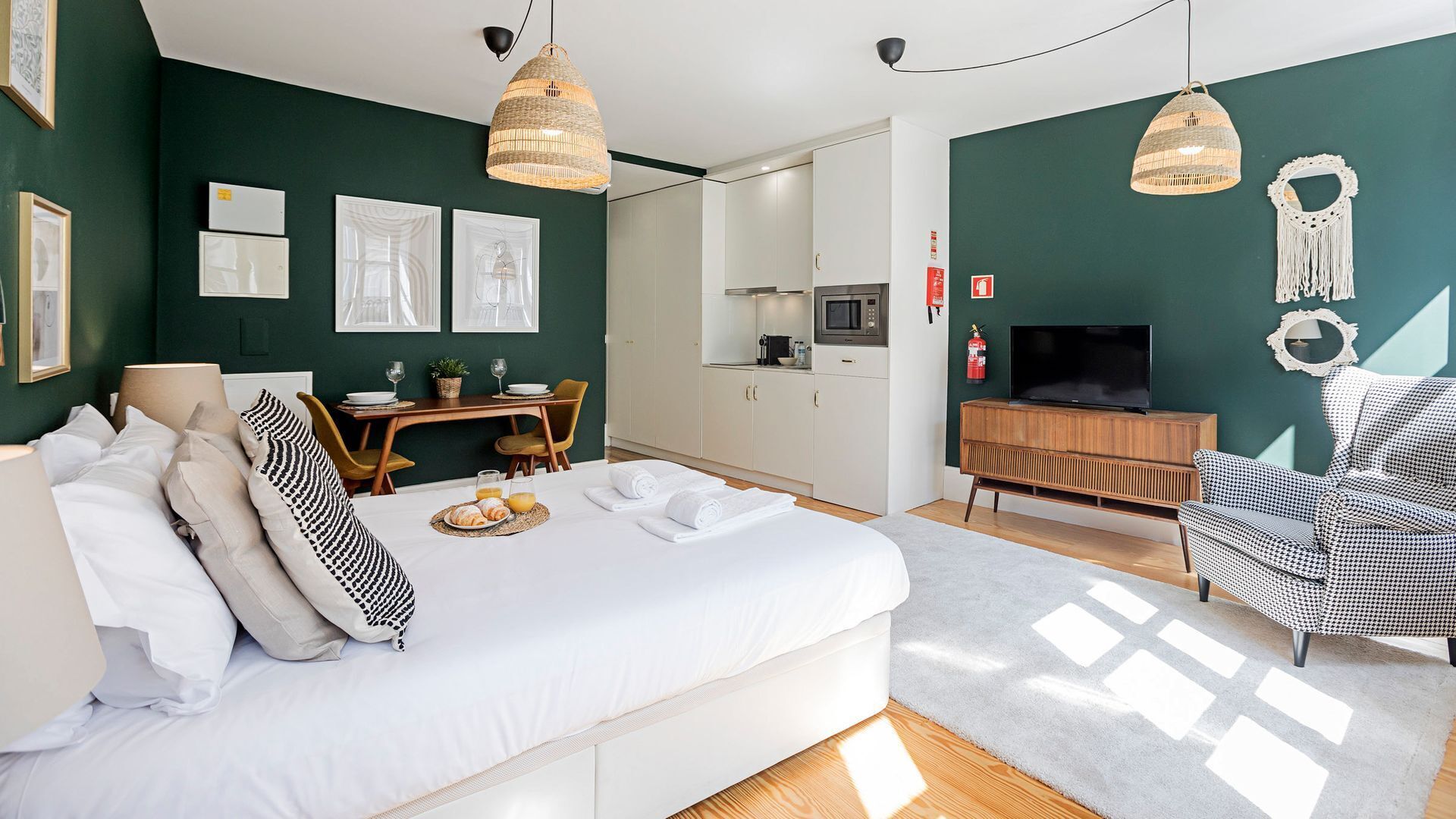 A modern bedroom with a bed, bedside table, and a dining area with a table and chairs.