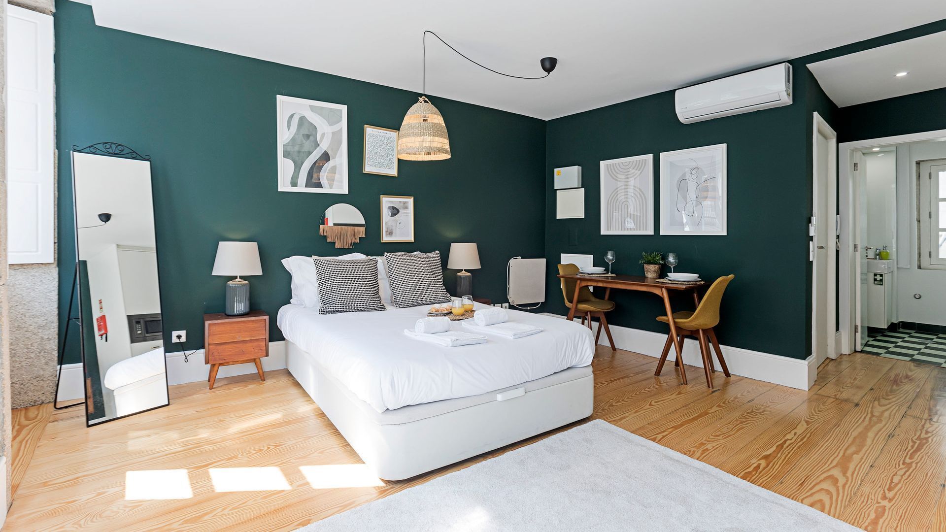 A modern bedroom with a large bed, bedside tables, a desk, and chairs.