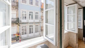 Una habitación con un ventanal grande que da a un edificio con varios balcones y vistas a la calle.