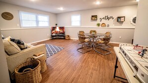 A cozy living room with a fireplace, a dining table with chairs, a sofa, and a pool table.