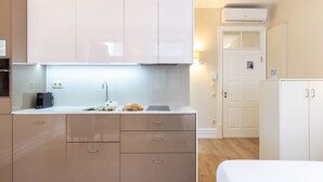 A modern kitchen with a built-in oven, a sink, and a countertop with a tablet and flowers. - Oporto Home Wine Cellars - Estúdio Standard - 1ºF (Vila Nova de Gaia)