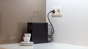 A coffee machine with a cup and saucer on a table, connected to a power outlet on the wall. - Oporto Home Wine Cellars - Estúdio Standard - 1ºF (Vila Nova de Gaia)