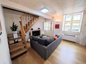 A living room with a wooden staircase, a grey sofa, a flat-screen TV, and a potted plant. - Civico36 Feels Like Home (Cagliari)