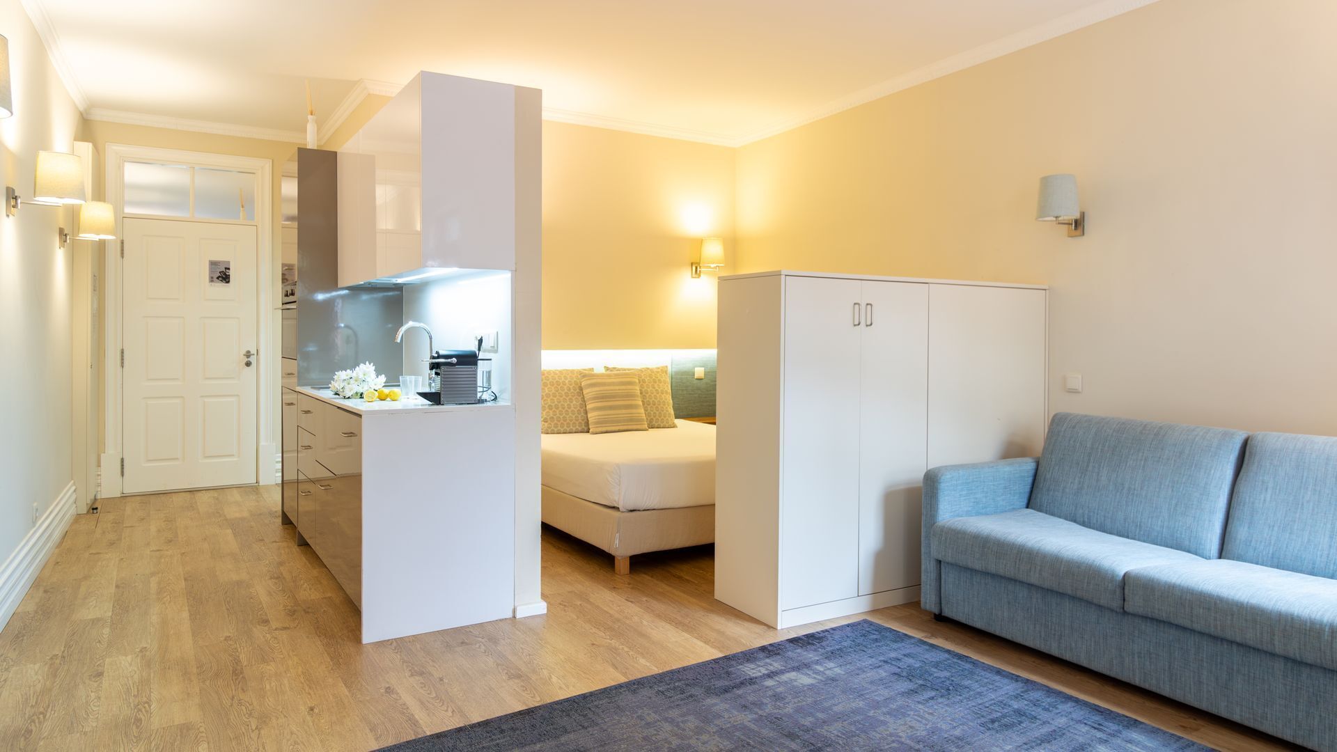 Un espacio habitable compacto con kitchenette, un sofá y una cama.
