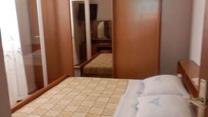 Una habitación pequeña con una cama, un armario y un espejo.