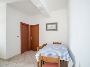A dining area with a checkered tablecloth, wooden chairs, and a framed picture on the wall. - Apartments Neva- Two Bedroom Apartment With Balcony (Selca)
