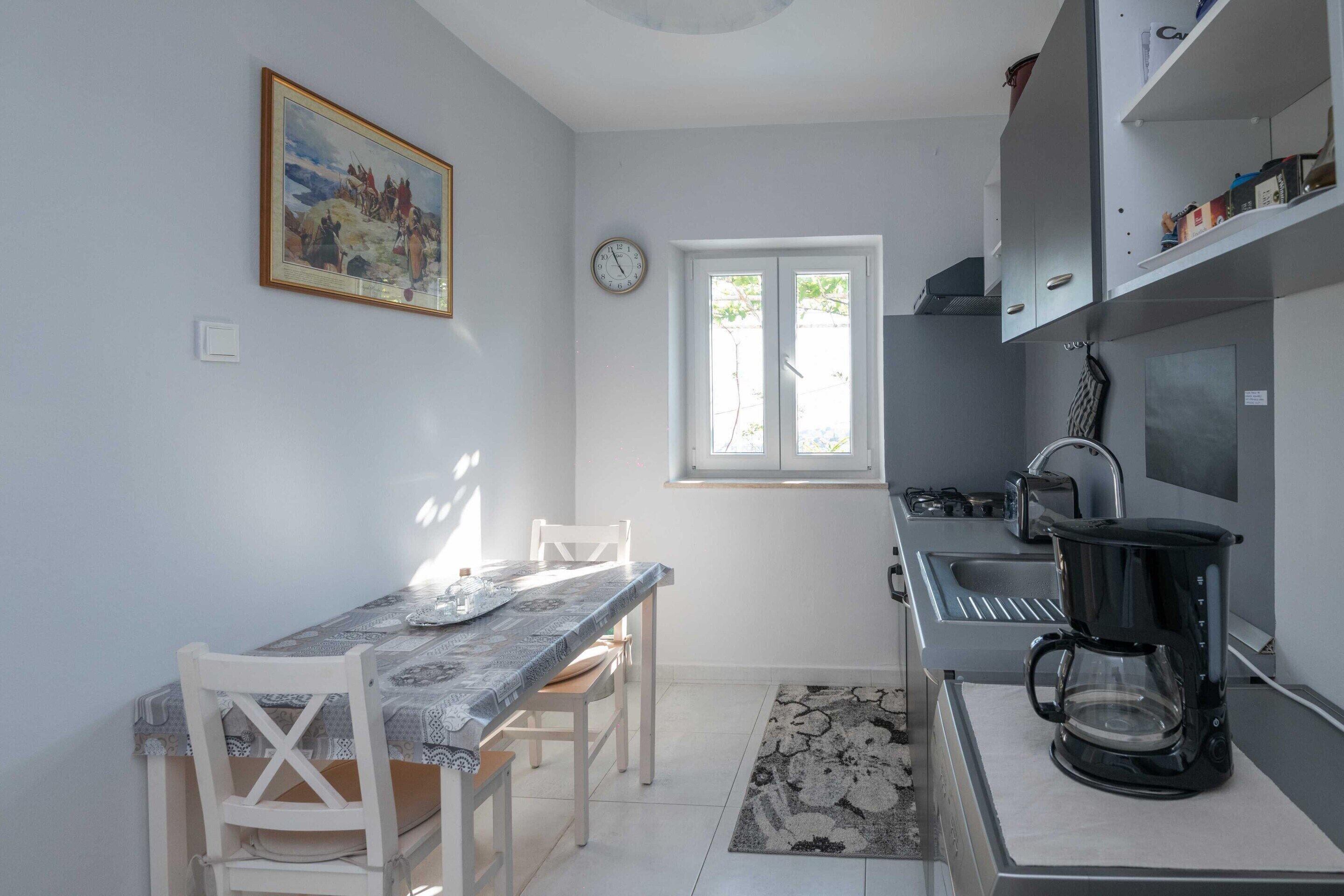 Uma cozinha compacta com mesa, cadeiras, cafeteira e janela com vista.