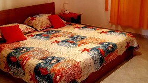 A bed with a patterned bedspread, red pillows, and a nightstand with a lamp. - Apartments Cumbelic - One Bedroom Apartment With Balcony and Sea View A1 (Mljet)