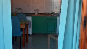 Una cocina con armarios verdes, un lavamanos y una mesa con sillas.