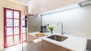 Una cocina moderna con un lavamanos de acero inoxidable, una cafetera y un florero con flores.