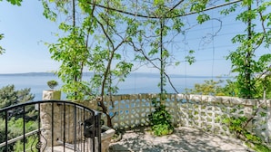A balcony with a stone wall, a metal gate, and a view of the sea. - Villa Kosa - Standard Double Room With Balcony and Sea View (Brela)