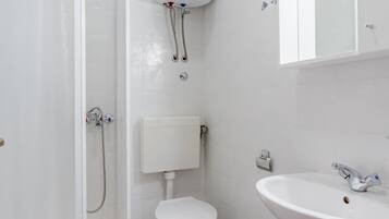 A bathroom with a shower, toilet, sink, and a water heater.