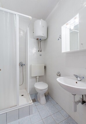 Une salle de bain équipée d’une douche, de toilettes, d’un lavabo et d’un chauffe-eau.