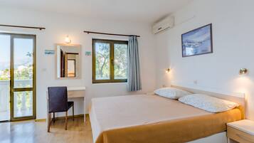 A bedroom with a bed, desk, chair, and a view of the outdoors.
