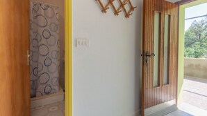 Ein Zimmer mit Holztür, einem gemusterten Vorhang, einer Wandleuchte und einem gefliesten Boden.