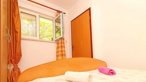 A bedroom with a wooden bed, a window with curtains, and a door. - Apartments Marko Peljesac - Standard One Bedroom Apartment With Balcony (Orebic)