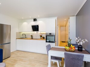 A modern kitchen with white cabinets, a built-in oven, and a stainless steel refrigerator. - Apartment Bianco - One Bedroom Apartment (Dubrovnik)