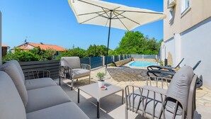 Une terrasse extérieure avec une piscine, des chaises longues et une table.