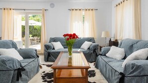 Un salon chaleureux avec deux canapés gris, une table basse en bois et un vase rempli de fleurs rouges.