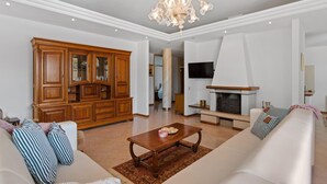 A spacious living room with a large wooden cabinet, a fireplace, a chandelier, and a television mounted on the wall. - Stylish Villa in Buje With Outdoor Kitchen (Buje)
