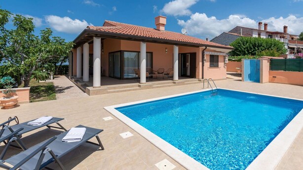 A poolside area with a clear blue pool, lounge chairs, and a covered patio. - Stylish Villa in Buje With Outdoor Kitchen (Buje)