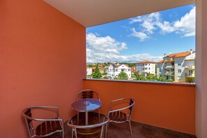 A balcony with orange walls, a round table, and four chairs. - Apartment in Medulin With Balconies (Medulin)