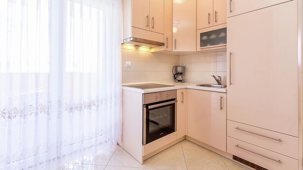 A compact kitchen with a stove, oven, sink, and upper cabinets. - Apartment in Medulin With Balconies (Medulin)