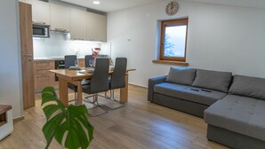 Eine moderne Küche mit Holzschränken, einem Esstisch mit Stühlen und einem grauen Sofa.