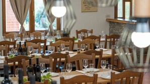 Ein Restaurant mit mehreren Holztischen und -stühlen, Weinflaschen und Gläsern auf jedem Tisch.