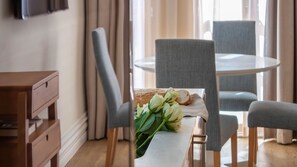 A dining area with a table, chairs, and a bouquet of flowers. - Oporto Home Wine Cellars - Estúdio com Varanda 3T (Vila Nova de Gaia)