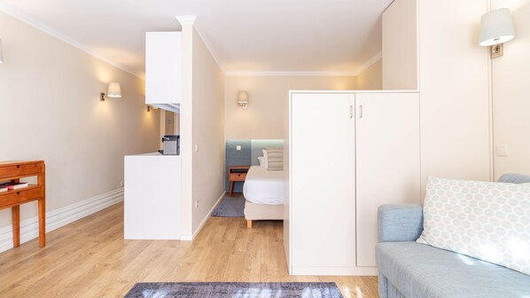 A compact room with a bed, a wardrobe, a desk, and a chair.