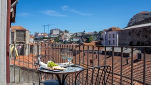 A terrace with a table set for two, overlooking a cityscape with historic buildings and a bridge. - Oporto Home Wine Cellars - Estúdio com Varanda 3T (Vila Nova de Gaia)