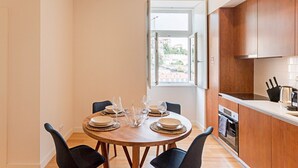 A dining area with a round table set for four, equipped with plates, bowls, and wine glasses. - Superb Flat w/ Balcony and AC by LovelyStay (Porto)