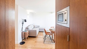 Un espace de vie compact comprenant un canapé, une table à manger et un four à micro-ondes.