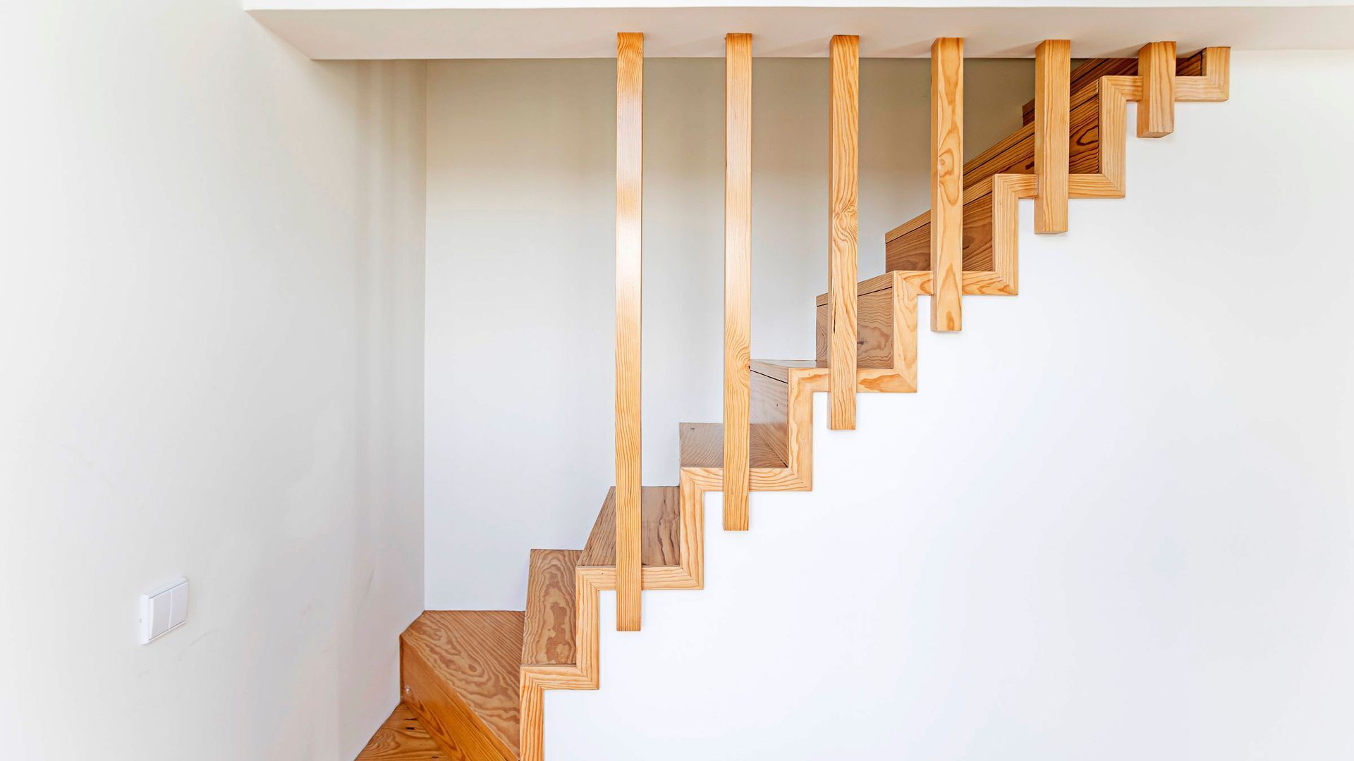 Un escalier en bois au design moderne, menant à l’étage supérieur.