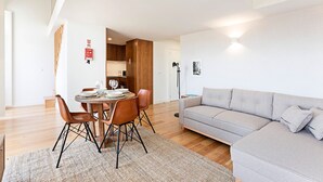 Un salon moderne avec un canapé gris, une table à manger en bois avec des chaises et un lampadaire.