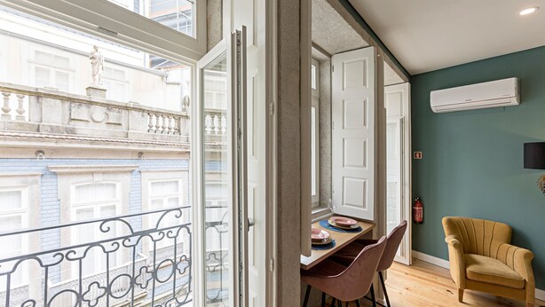 An interior with a dining area, a chair, a table, and a view of a building with balconies. - Turquoise Flat w/ AC & Balcony by LovelyStay (Porto)