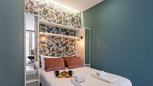 A bed with floral wallpaper, a bedside table with a lamp, and a breakfast tray on the bed. - Turquoise Flat w/ AC & Balcony by LovelyStay (Porto)