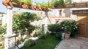 A garden with a pergola, a stone wall, and a wooden door. - Apartments Gaura - Comfort One-bedroom Apartment With Terrace (Dubrovnik)