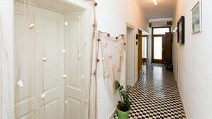 Un pasillo con piso a cuadros, una planta verde y un tapiz decorativo.