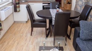Ein kompakter Wohnbereich mit einer Küchenzeile, einem Essbereich mit rundem Tisch und Stühlen sowie einer Couch.