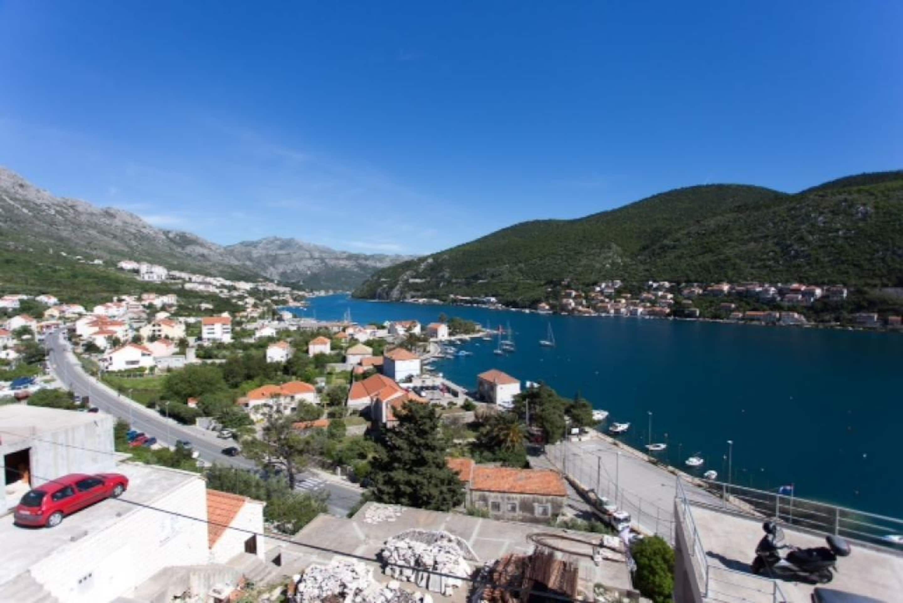 A coastal town with a marina, buildings, and a road leading to the water.