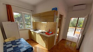 Eine kleine Küche mit Holzschränken, einem Spülbecken und einem Fenster.