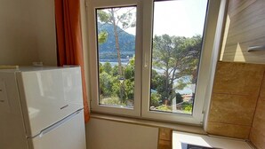 Eine kleine Küche mit Kühlschrank, Herd und einem Fenster mit Blick auf eine Berglandschaft.