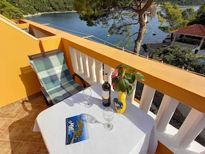 A balcony with a table set for two, a bottle of wine, and a glass. - Apartments Vinko Mljet- One-bedroom Apartment With Terrace (Mljet)