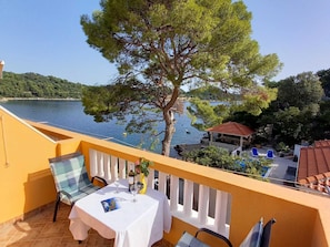A balcony with a table set for two, overlooking a lake and a gazebo. - Apartments Vinko Mljet- One-bedroom Apartment With Terrace (Mljet)
