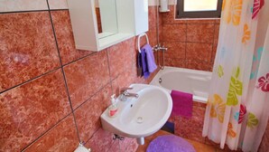 A bathroom with a sink, mirror, and shower.