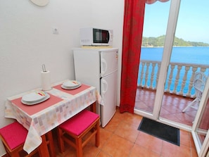 Ein kleiner Balkon mit Tisch für zwei Personen, einer Mikrowelle und einem Kühlschrank.